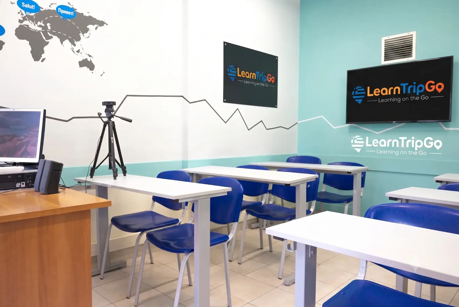 Modern classroom at Papavarsami Language School with world map, white desks and LearnTripGo branding